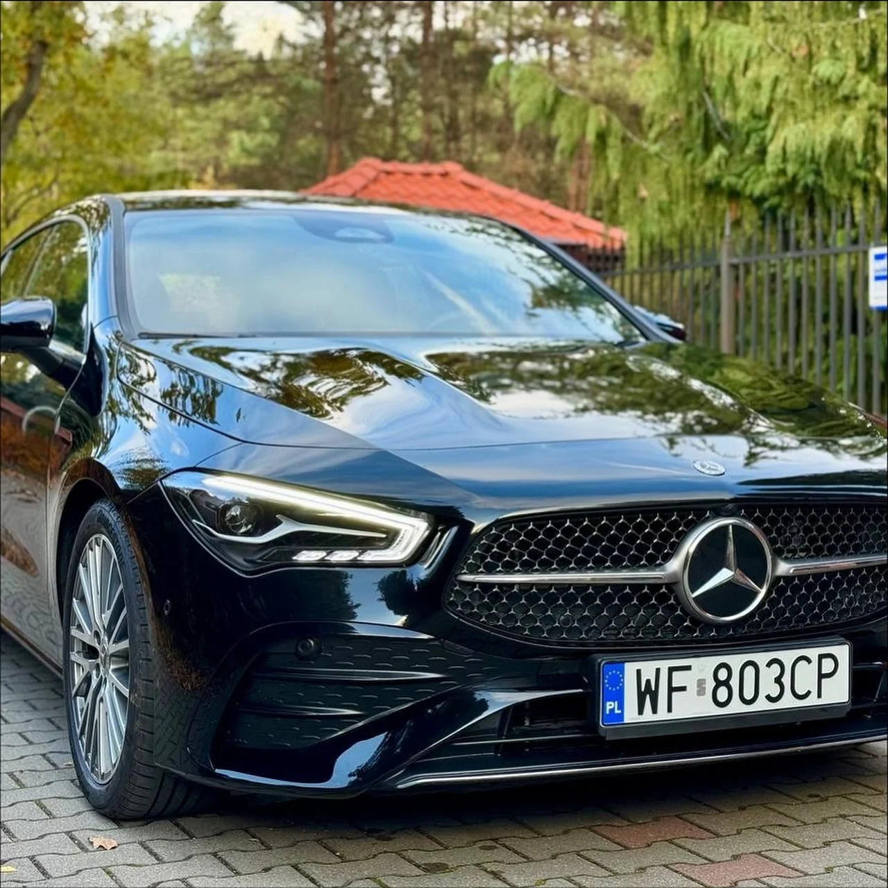 Czarny Mercedes w idealnym stanie zaparkowany na podjeździe, widok z przodu.