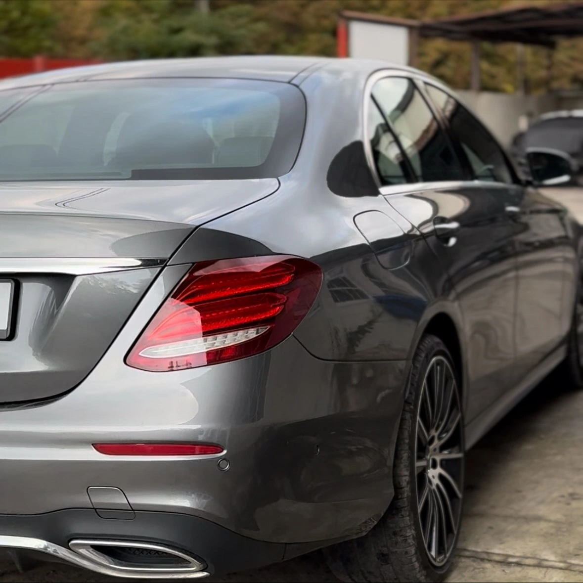 Tył szarego Mercedesa klasy E w dobrym stanie, widok z lewej strony.